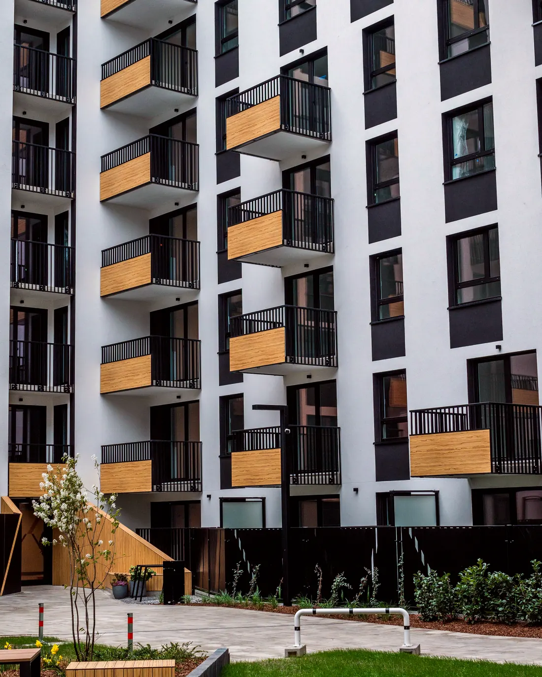 Edificio residencial blanco y grafito con balcones de madera sobre un jardín interior — referencia del loft Jardín en Surco
